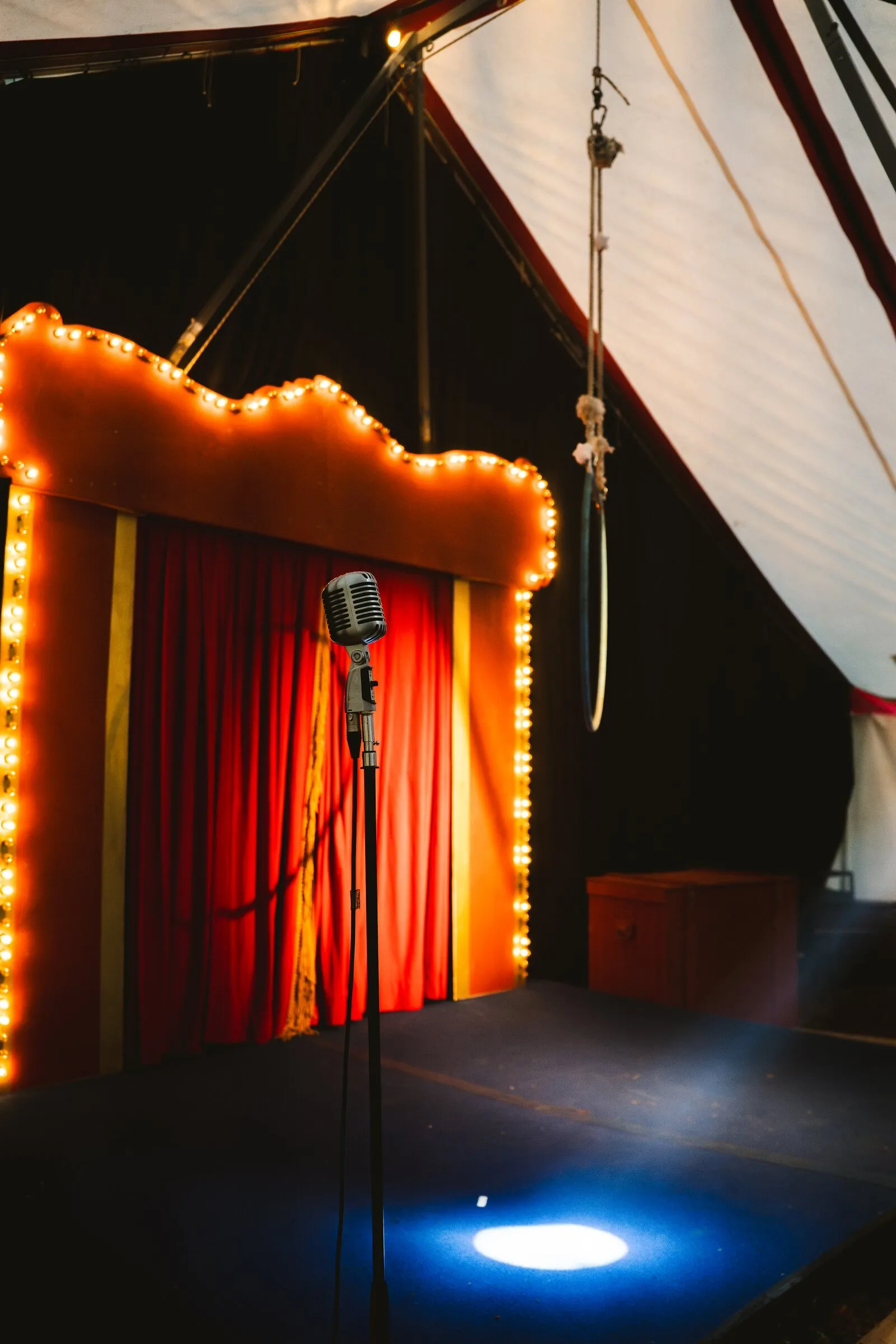 The empty Kuroneko Circus stage with a vintage microphone in a pool of spotlight under the marquee