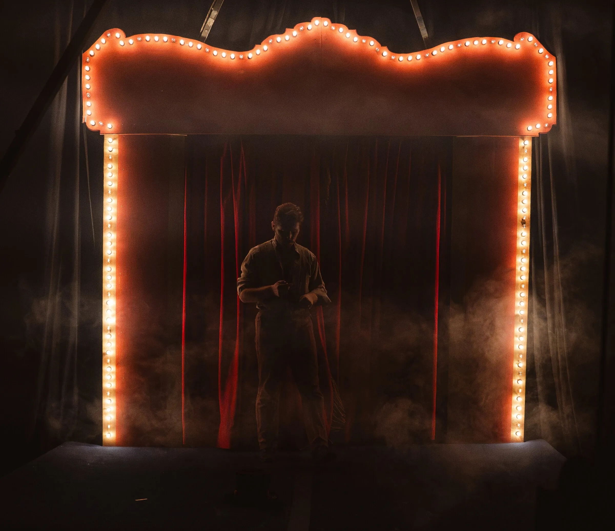 Smoke drifting across the Kuroneko Circus stage beneath the marquee arch before the show